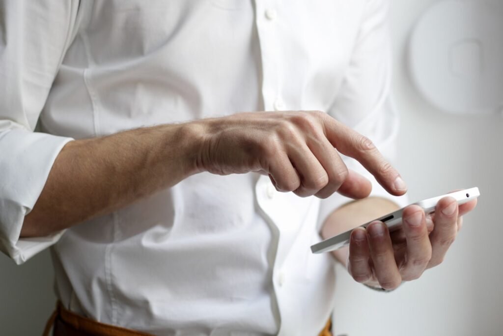 Person in white shirt tapping on a smartphone to place a water delivery order via WhatsApp