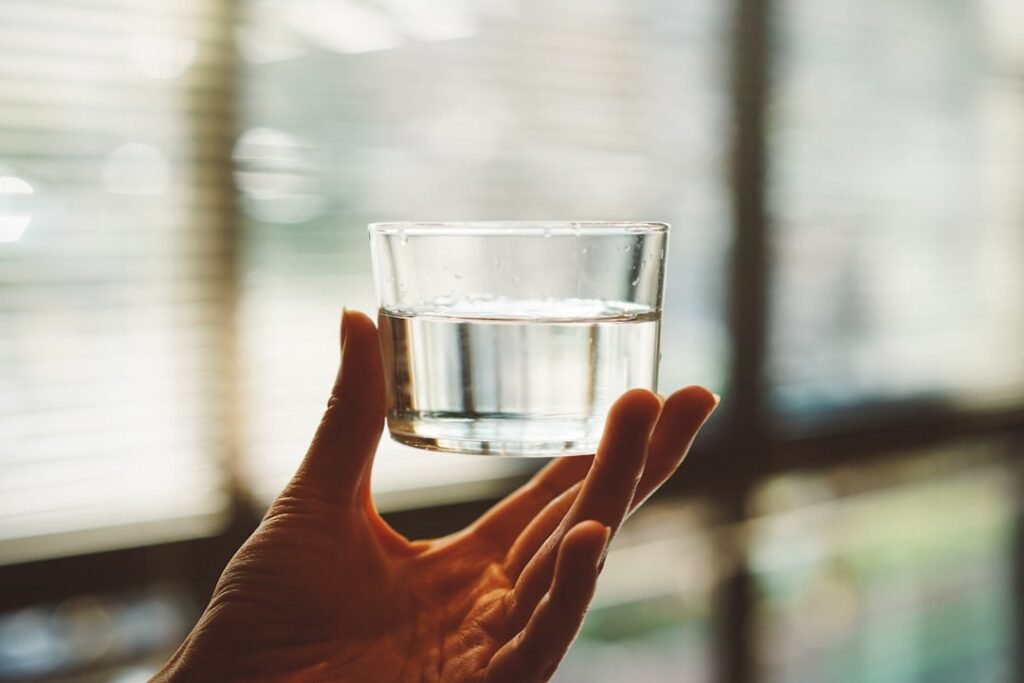 A glass of clear drinking water held up to the light to check for cloudiness and particles