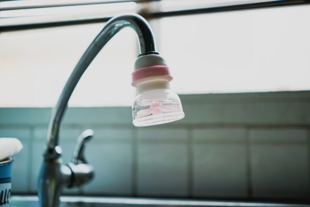 A water filter attached directly to a kitchen faucet tap head, a common first-line filtration step for households