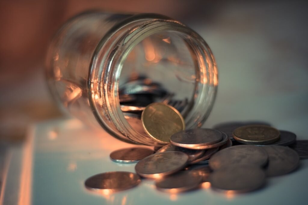 Coins spilling from a glass jar representing household savings from a monthly water delivery membership plan