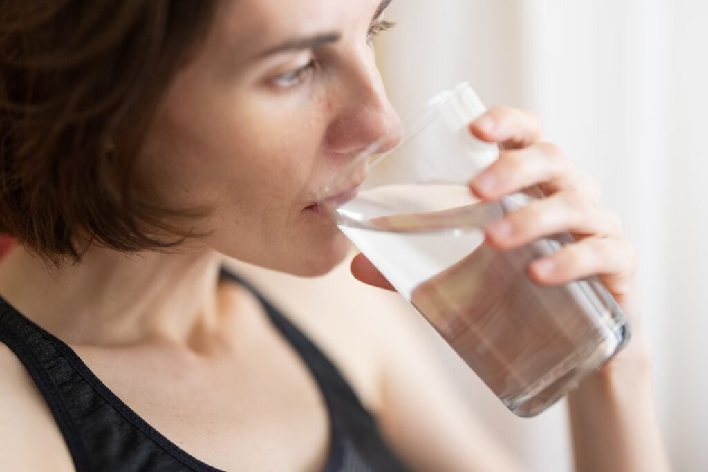 Woman drinking a glass of fresh clean water at home