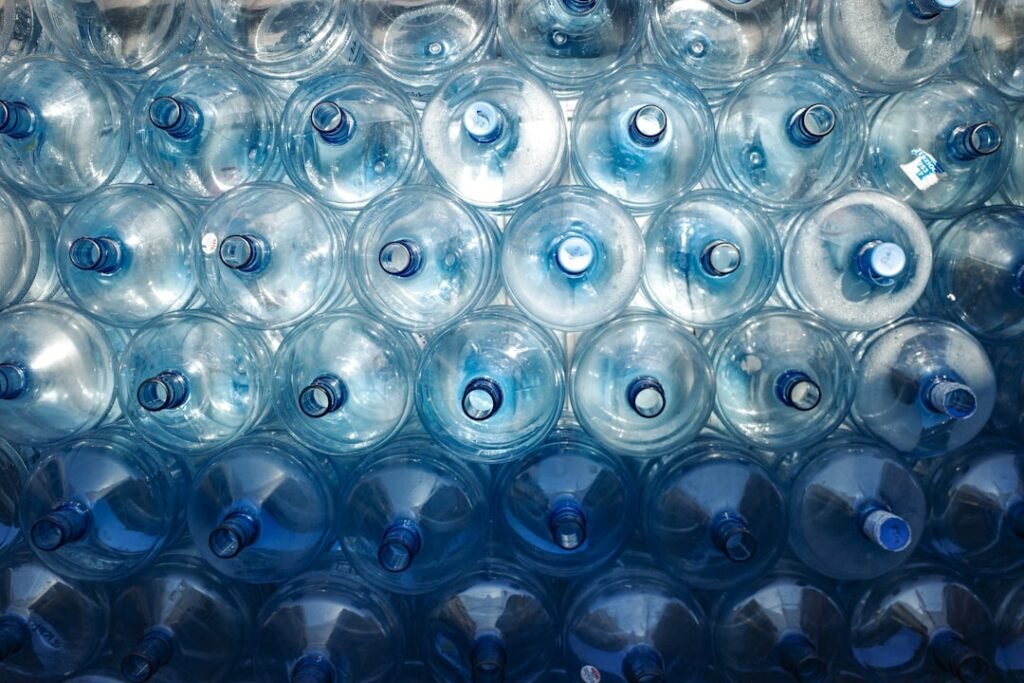Stacked 19-liter water cooler bottles seen from above, representing monthly bottle quantities in a water delivery plan