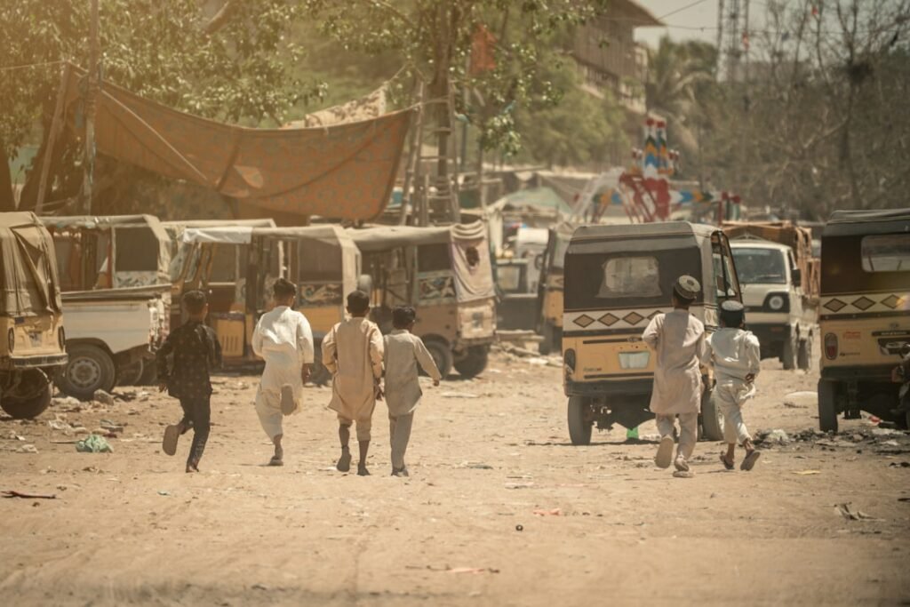 Children walking through a hazy, sun-baked street in Pakistan, illustrating the intense summer heat that makes safe water access critical in Multan