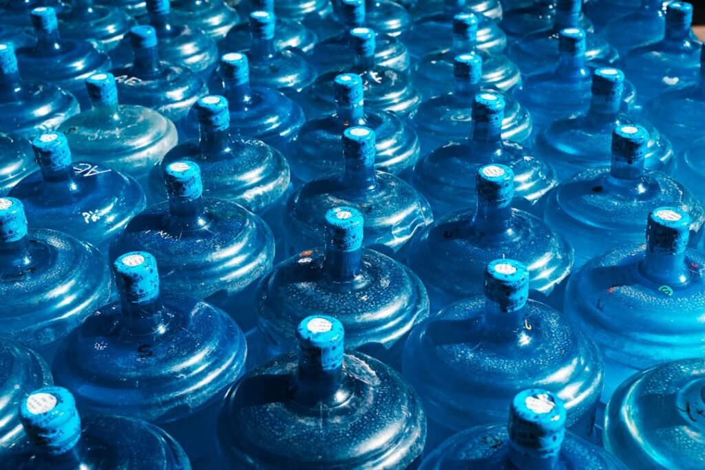 Rows of blue 19-litre water cooler jugs at a water bottling facility