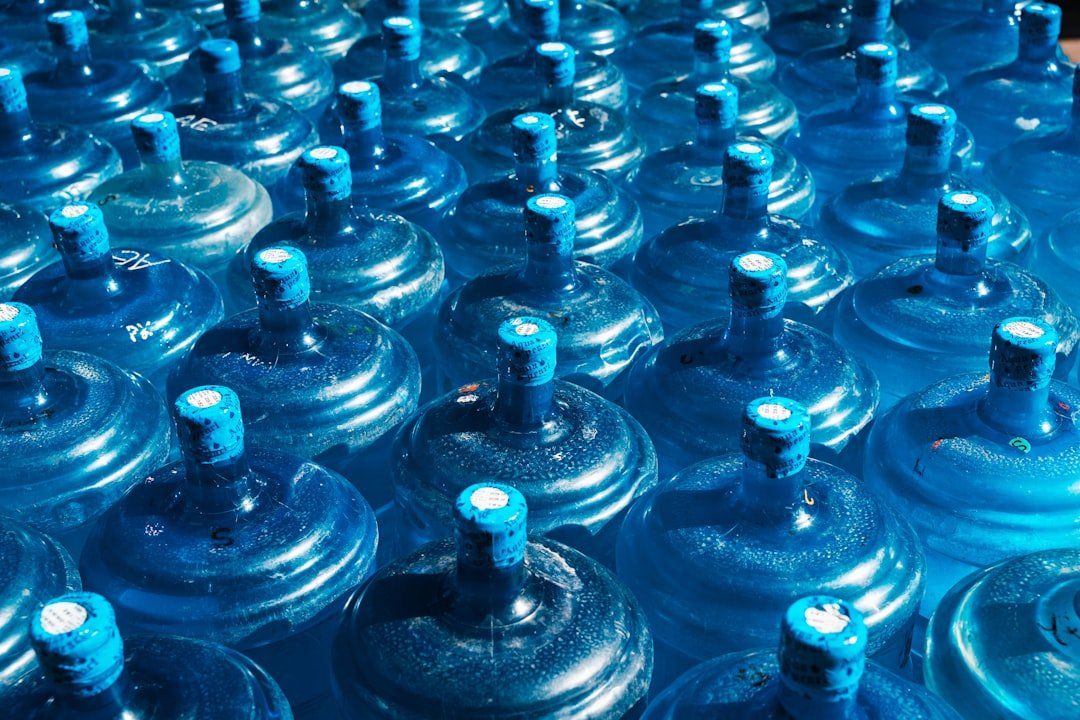 john-towner-3Kv48NS4WUU-unsplash Rows of blue 19-liter water cooler jugs ready for household delivery — Noorè-Aab water delivery Multan
